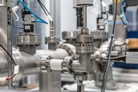 Primer plano de equipo científico con tuberías, conectores y sensores en un entorno de laboratorio.