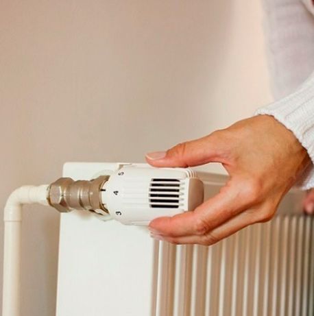 Una persona está ajustando un termostato en un radiador.