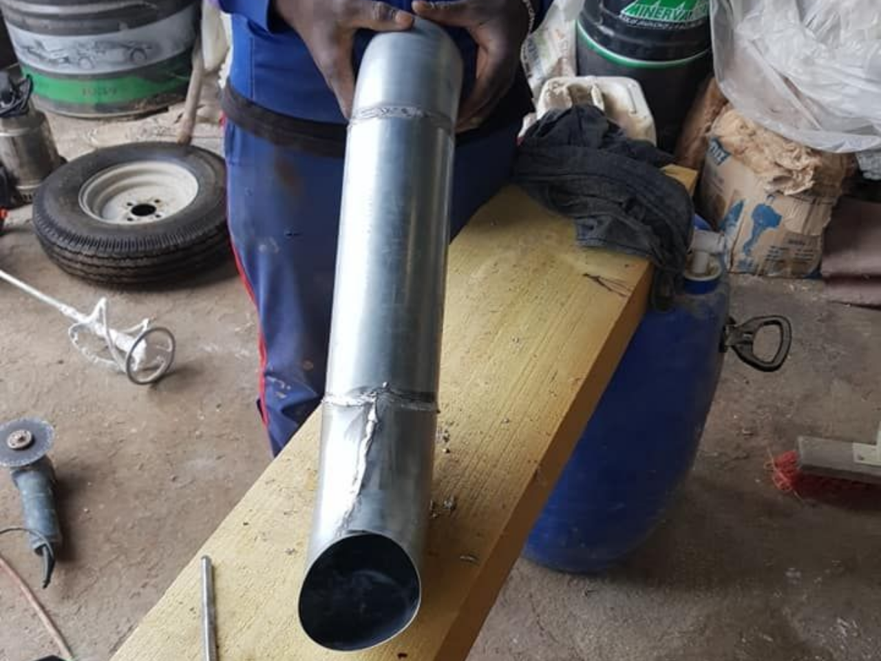 Un artisan tient dans les mains un élément de zinguerie fait sur mesure.