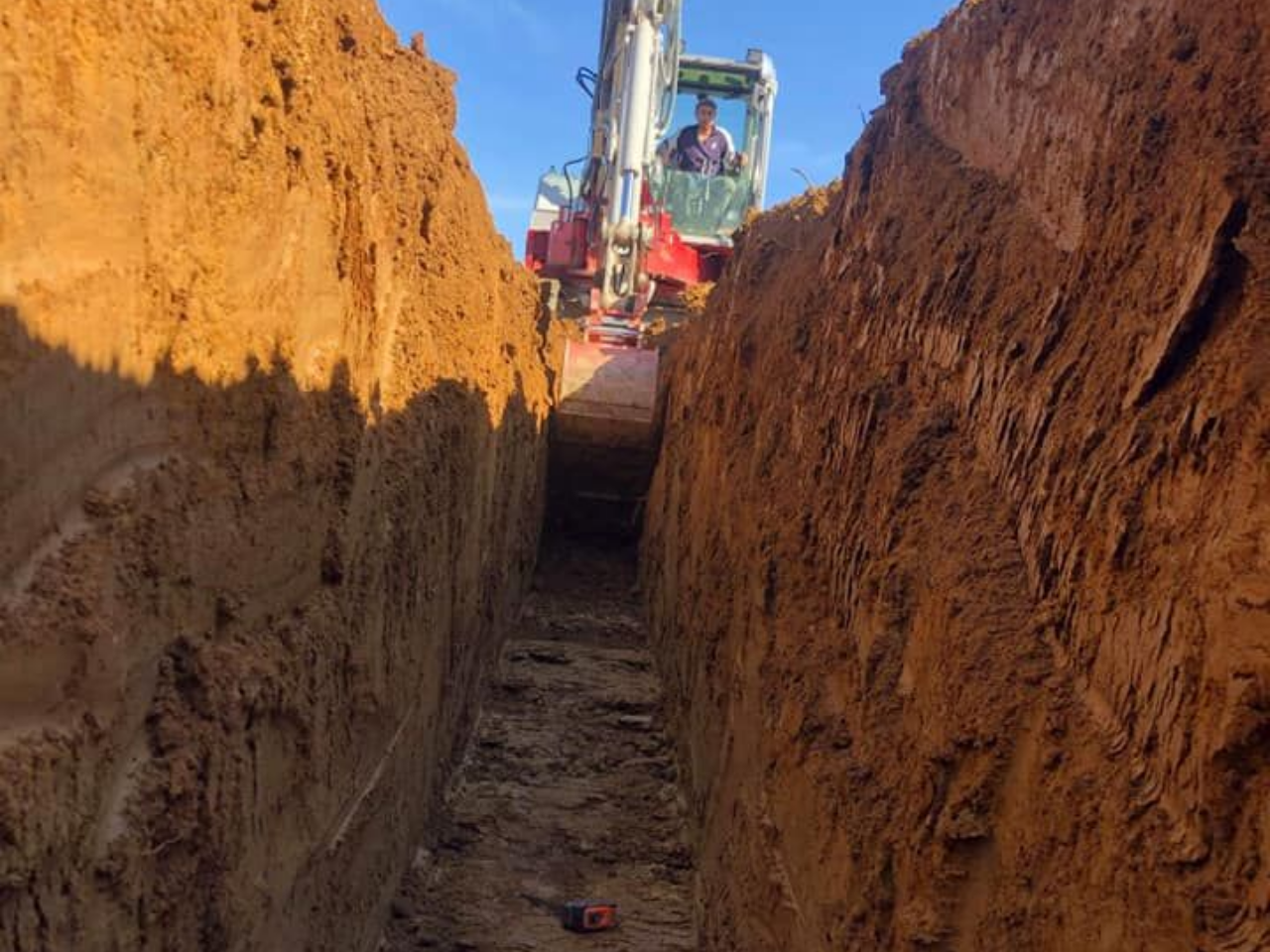 Une pelle creuse une tranchée dans la terre.