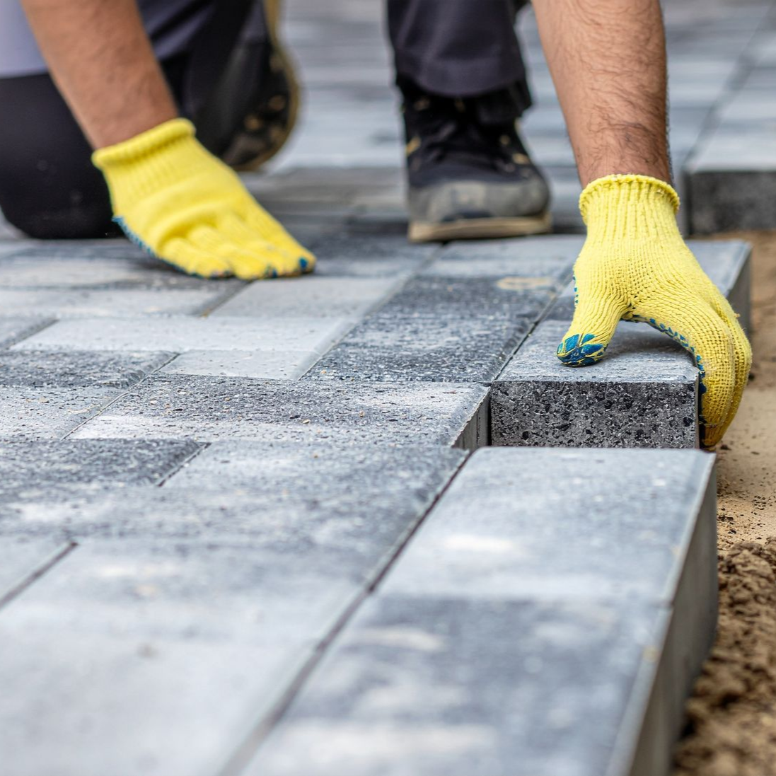 Un artisan pose des pavés pour faire un allée de jardin.