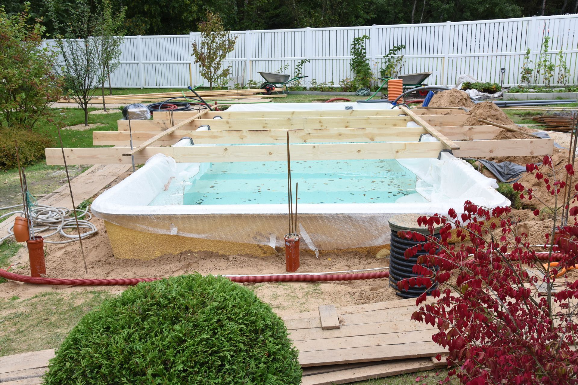 Construction d'une piscine entourée d'arbustes.