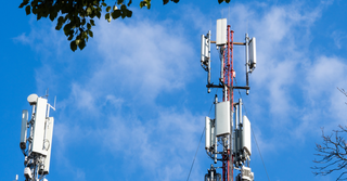 Deux tours de téléphonie mobile se dressent contre un ciel bleu avec des nuages.