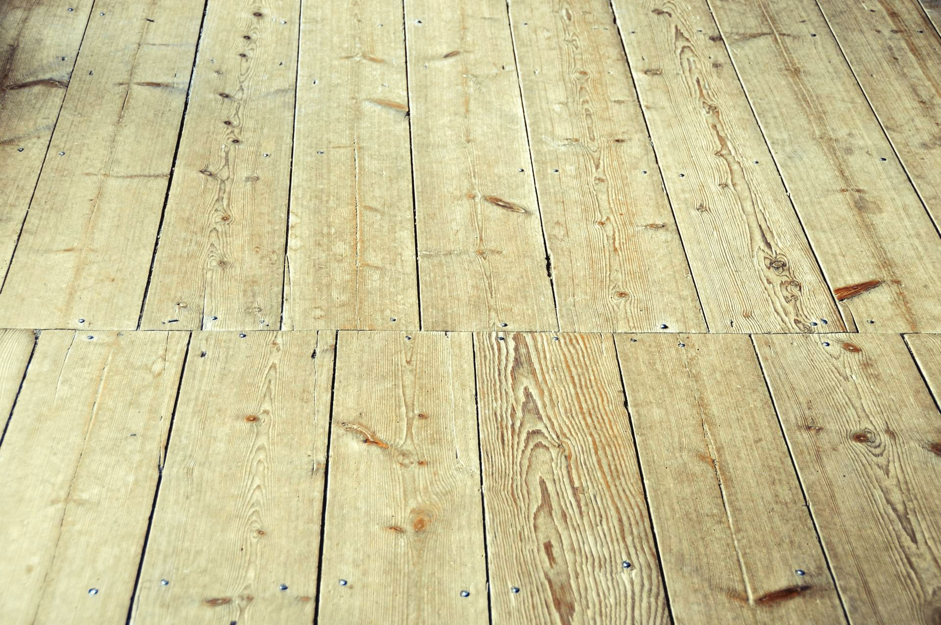 Gros plan sur des lames de parquet rustiques en bois clair, posées en quinconce et laissant apparaître le grain du bois.