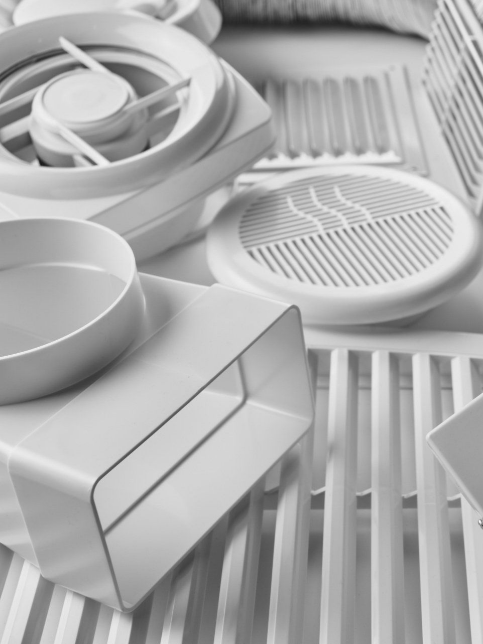 Composants de ventilation en plastique blanc, notamment grilles, bouches d'aération et raccords de conduits.