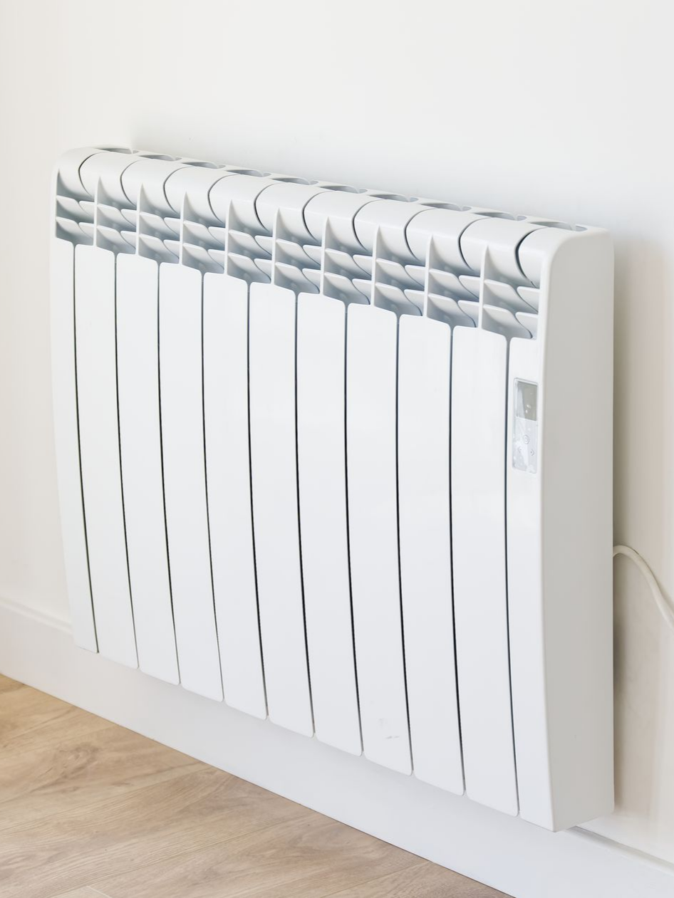 Radiateur électrique blanc fixé au mur ; parquet visible.