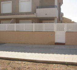 Una casa con una valla blanca alrededor y una puerta blanca.