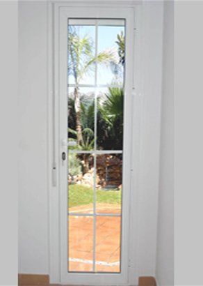 Una puerta blanca con vista a un jardín a través de ella.