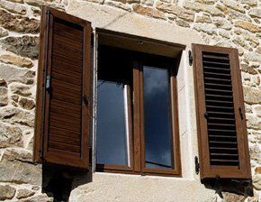 Una ventana con contraventanas de madera en una pared de piedra.