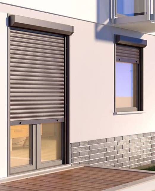 Zwei Fenster mit geschlossenen, braunen Rollläden an einer weissen Gebäudefassade, tagsüber.