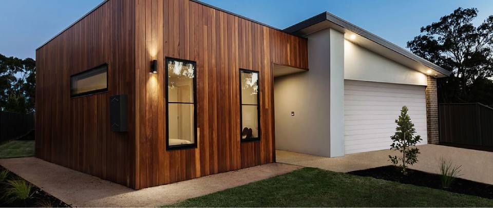 Modernes Haus mit Holzverkleidung und Garage. Der Abendhimmel ist blau.