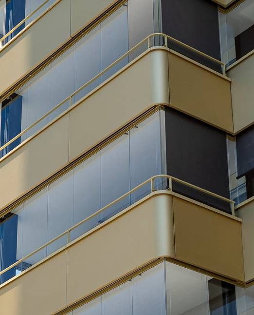 Beige und gläserne Balkone an der Ecke eines modernen Gebäudes. Dunkle Beschattungen auf einem Balkon.