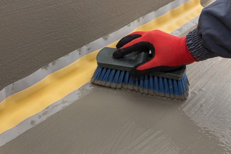 Izonil Putz wird mit einer Bürste auf einem Boden verteilt.