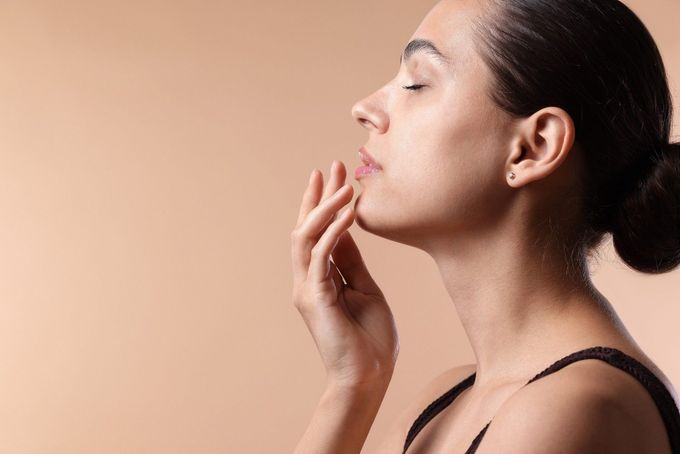 Una persona con los ojos cerrados toca suavemente su mandíbula con las yemas 