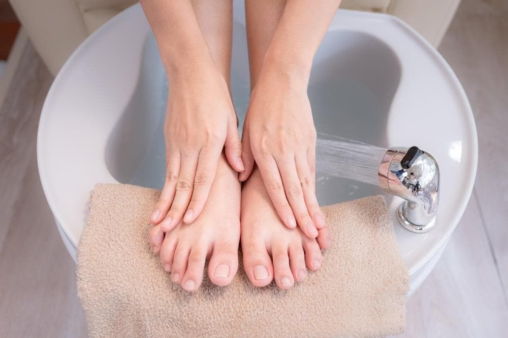 Una persona está sentada con los pies descalzos sobre una toalla color 