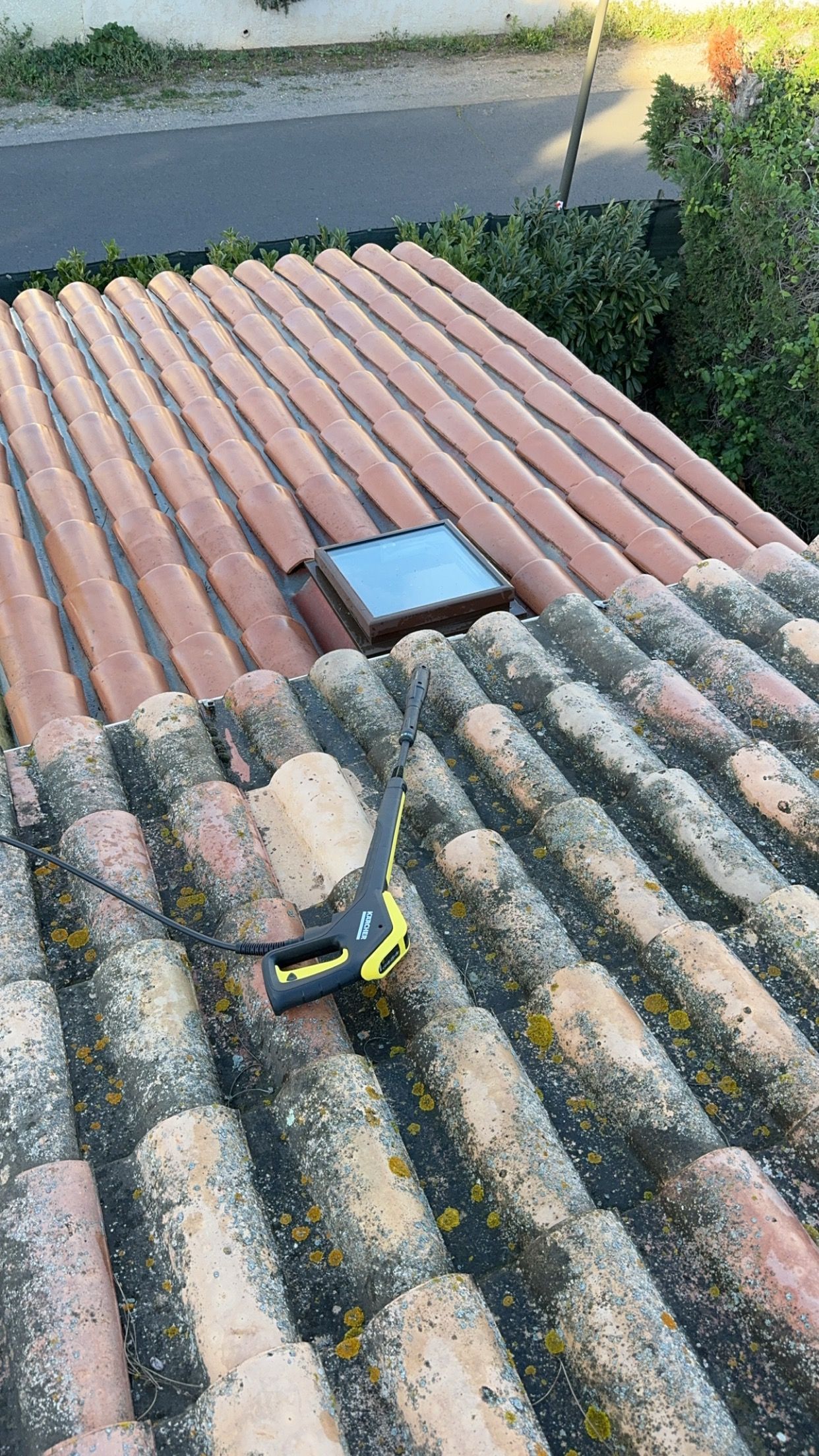 Un champ herbeux avec une tondeuse à gazon au premier plan, menant à un petit hangar et une clôture sous un ciel partiellement nuageux.
