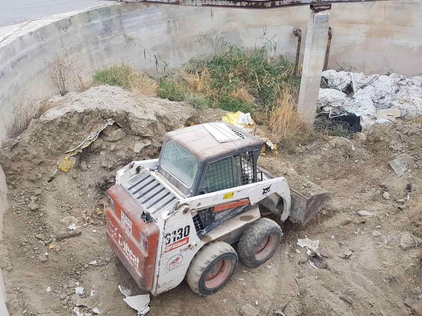 Cargadora compacta Bobcat S230 en un sitio de construcción, moviendo tierra y escombros.