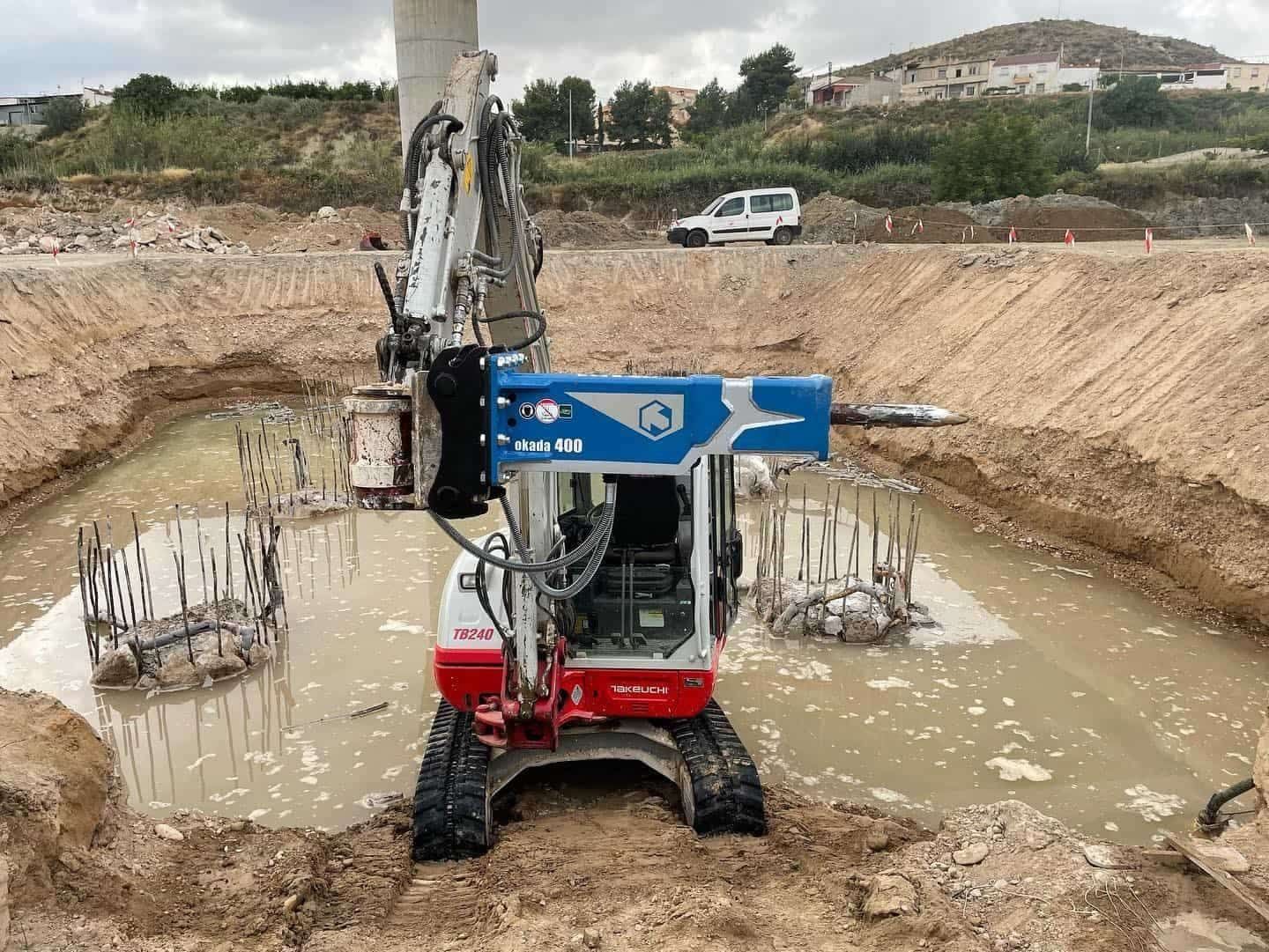 Excavadora en pozo fangoso perforando soportes de construcción.