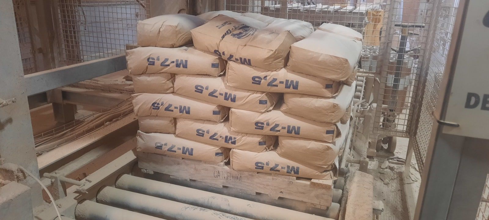 Contenedor rojo en un camión blanco estacionado en un camino de tierra, árboles en el fondo, cielo azul.