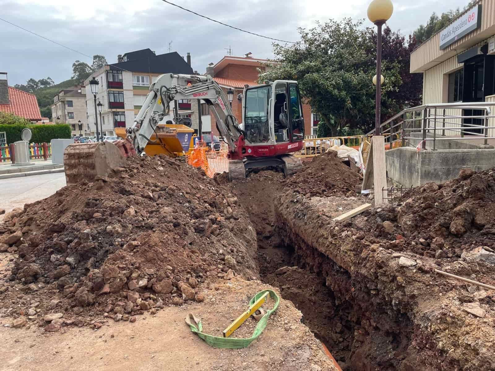 Sitio de construcción con una excavadora cavando una zanja en una calle.