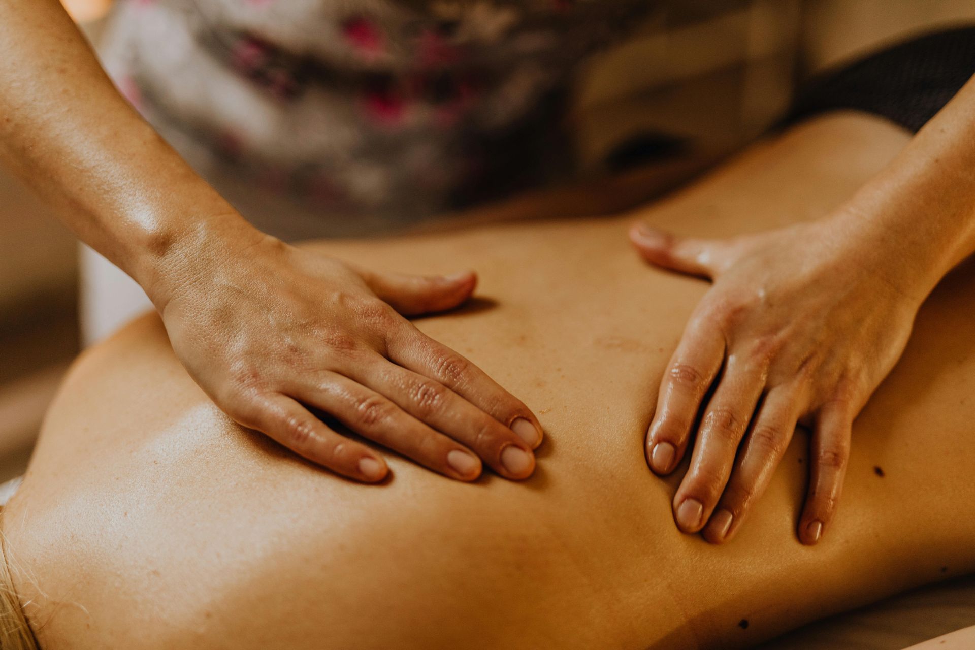 Hände massieren den Rücken einer Person, vermutlich in einem Spa.