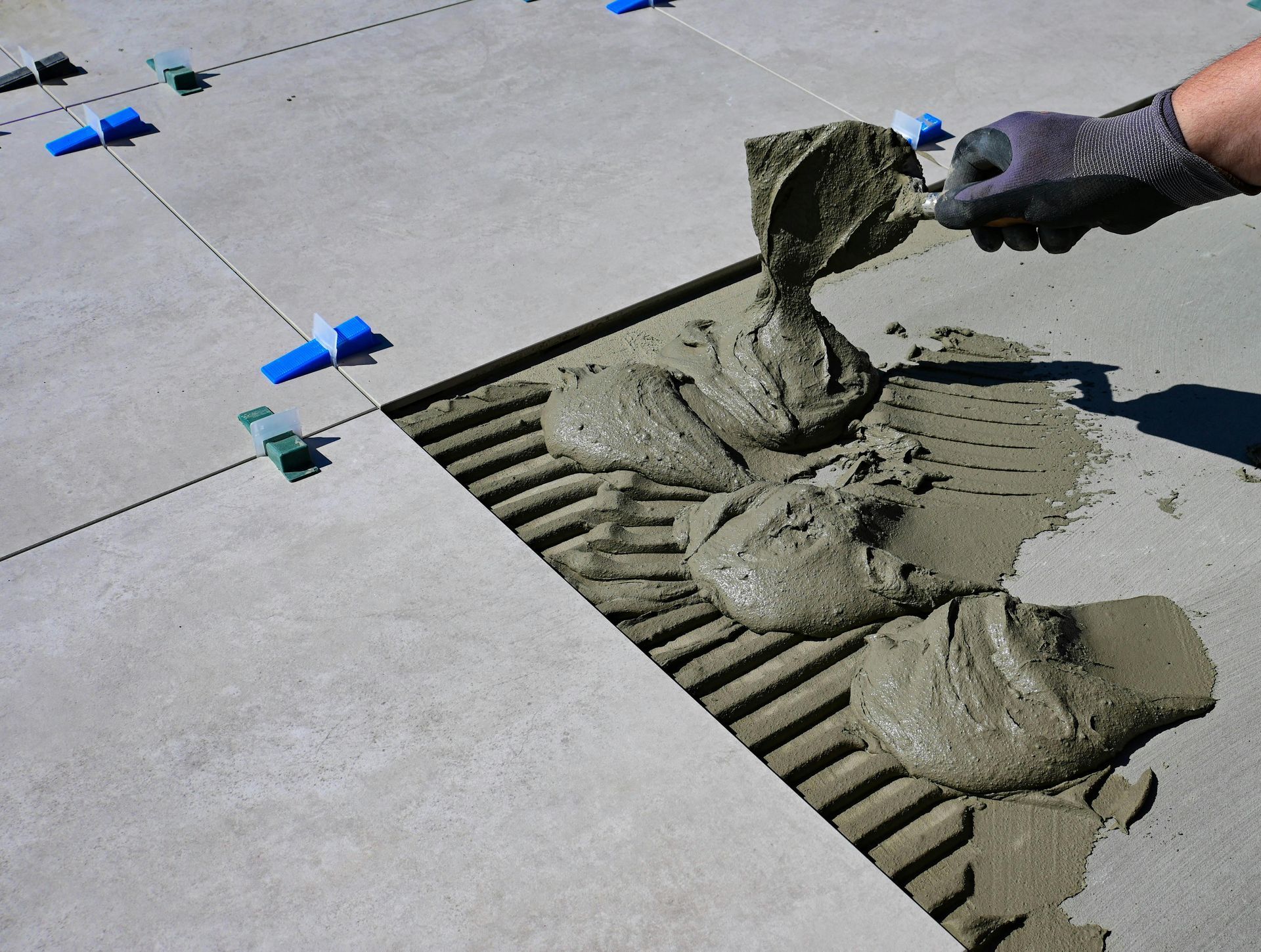 Un ouvrier prépare un sol à la pose de carrelage.