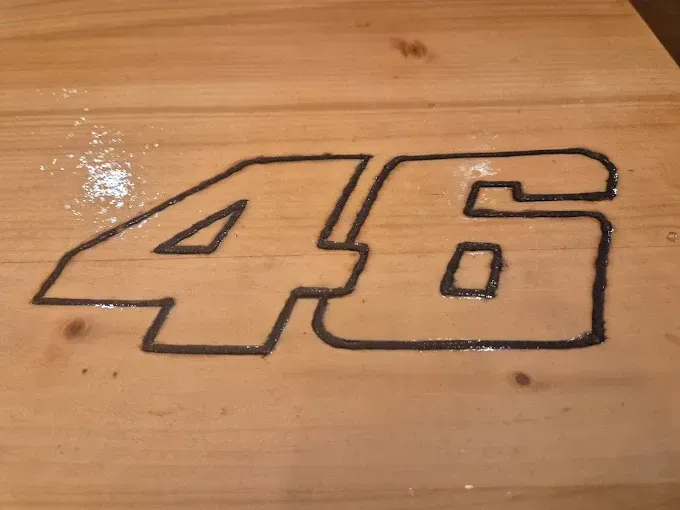 El número 46, delineado en negro, está pintado sobre un suelo de madera.