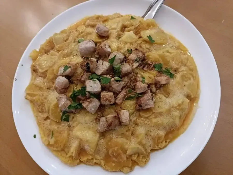 Plato de pasta cremosa cubierto con carne picada y champiñones, adornado con hierbas.