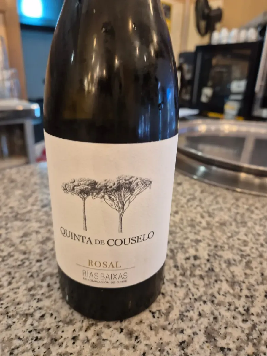 Botella de vino con etiqueta color crema sobre una encimera de granito en un restaurante.