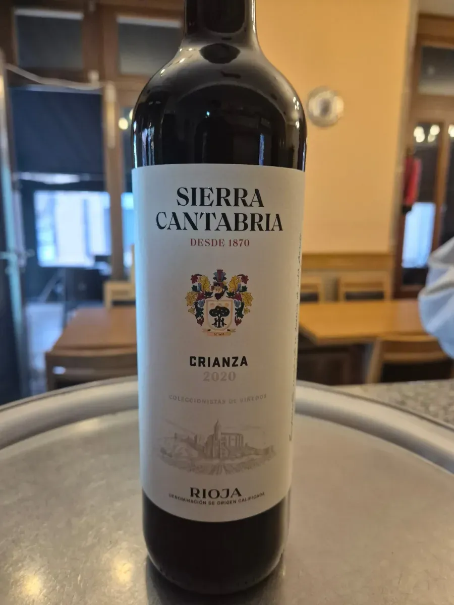 Botella de vino tinto Sierra Cantabria Crianza sobre la mesa de un restaurante, con la etiqueta hacia adelante.