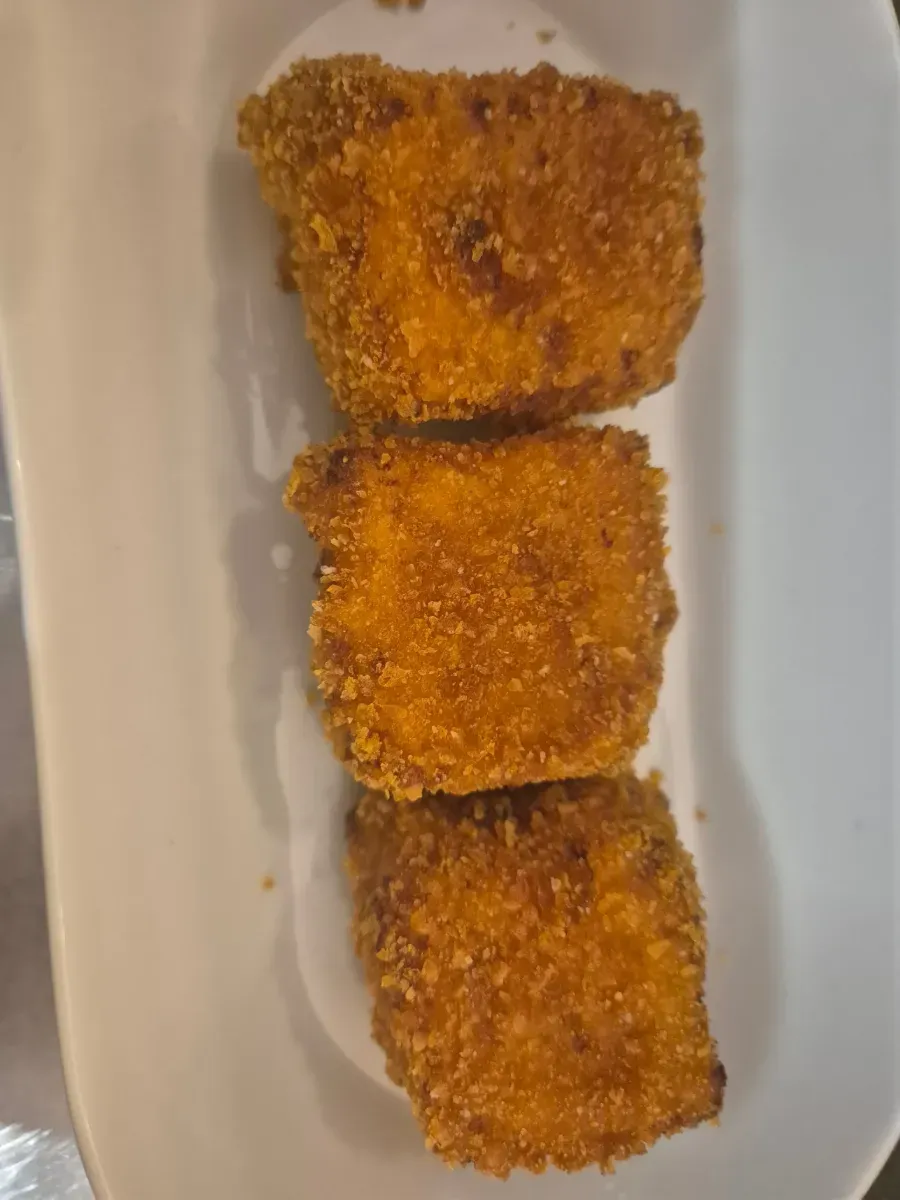 Tres nuggets empanizados y fritos en un plato blanco.