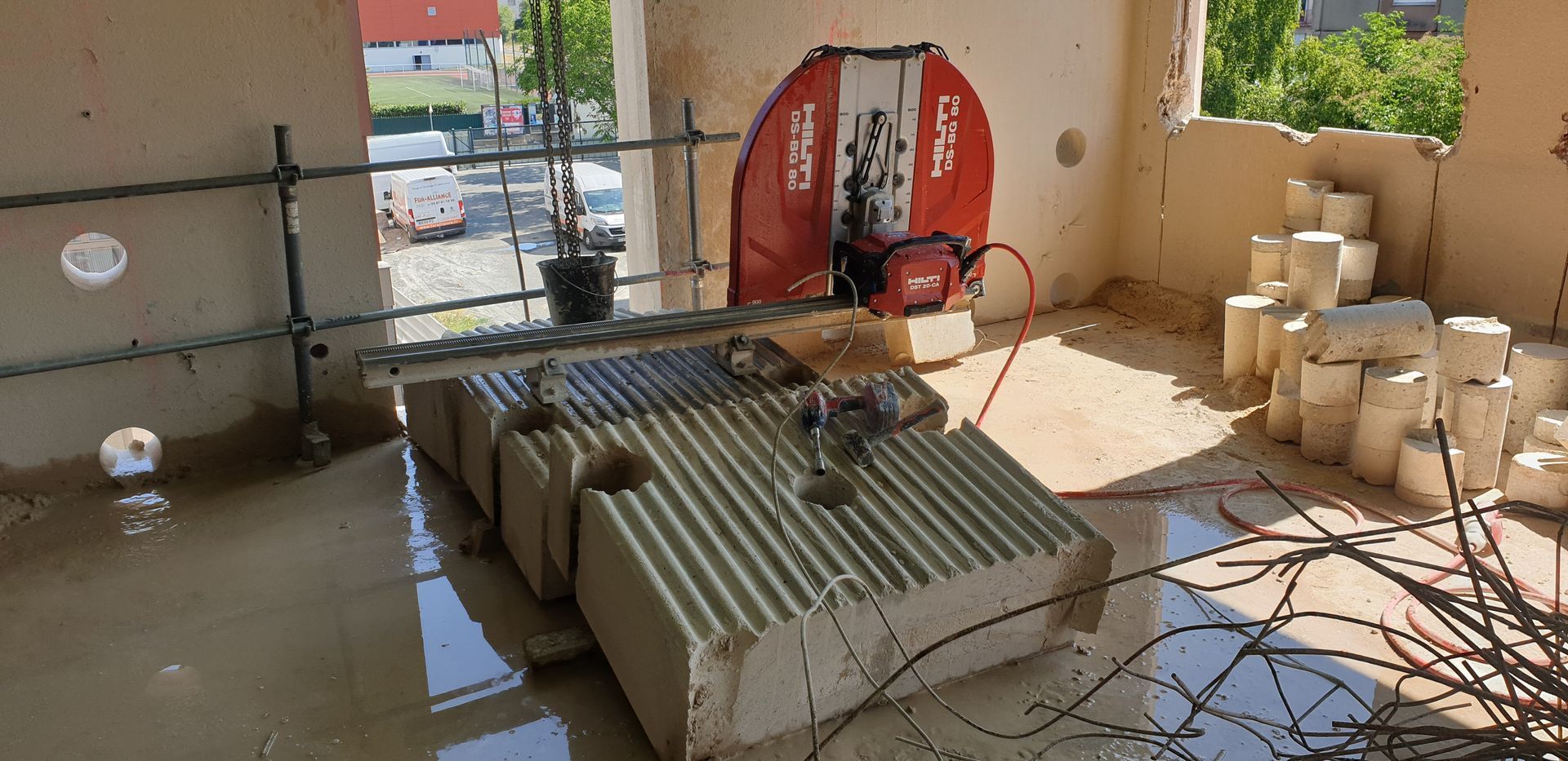 Un chantier de construction avec une grande scie rouge qui découpe des blocs de béton.