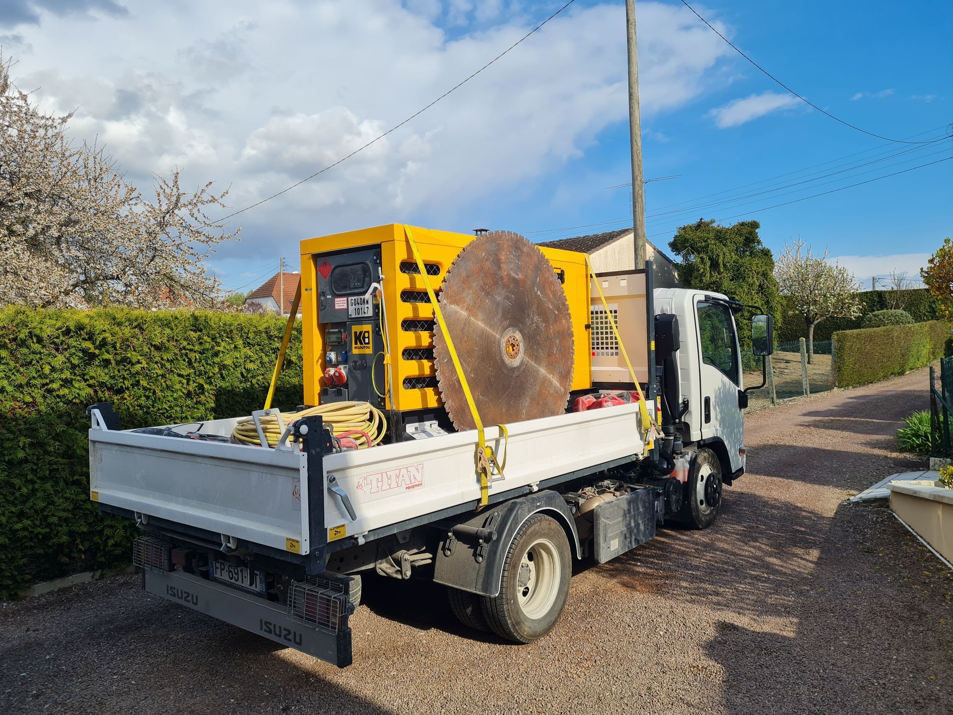 Générateur jaune et grand disque métallique fixés sur le plateau d'un camion blanc.