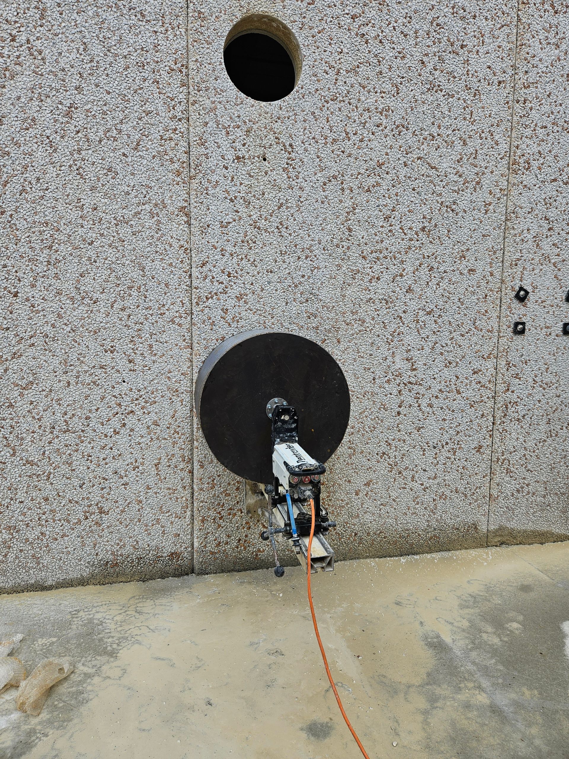 Une machine perce un grand trou dans un mur de granit ; un autre trou est déjà présent.