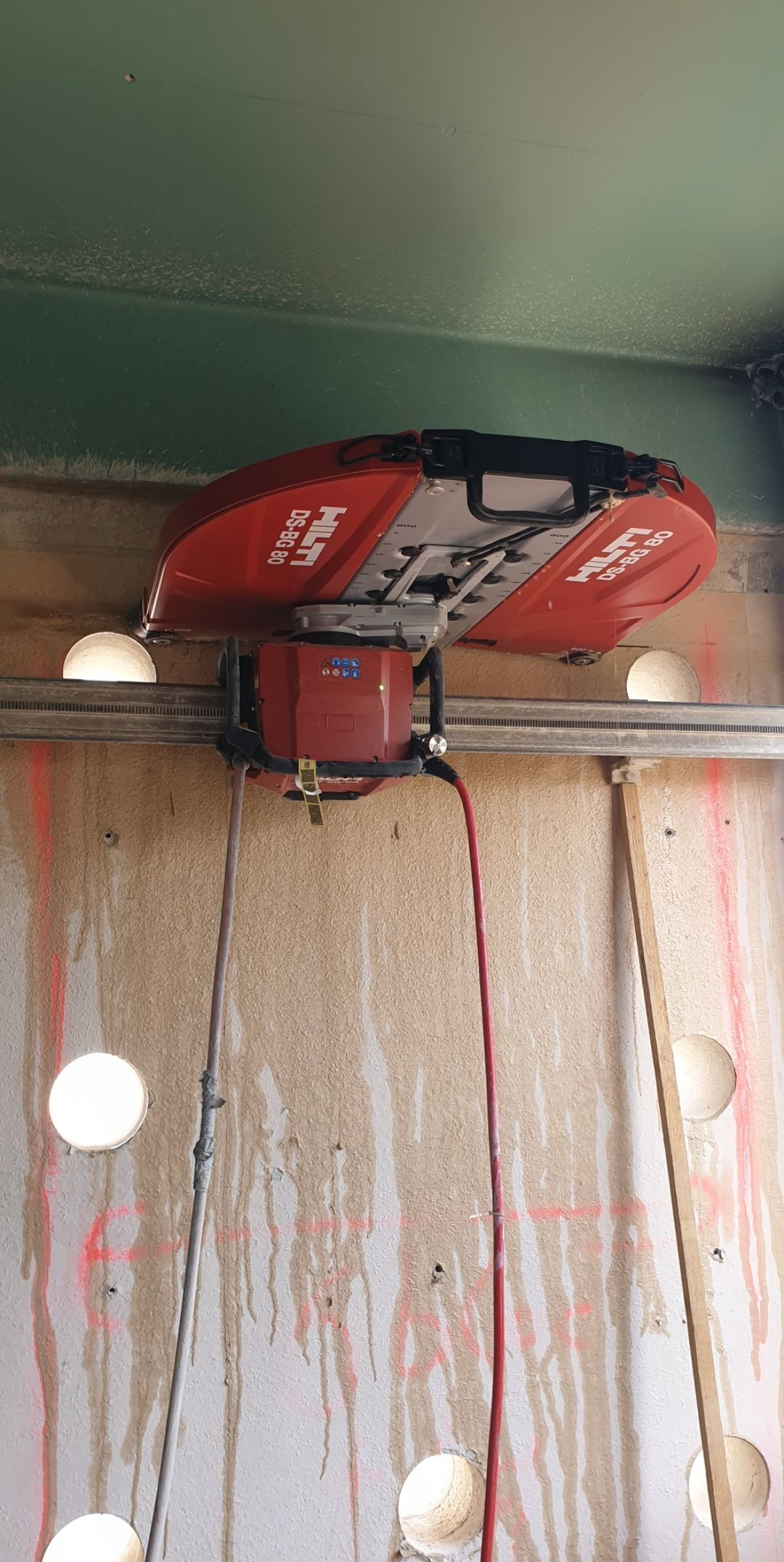 Outil de construction rouge perçant des trous dans un mur en béton.
