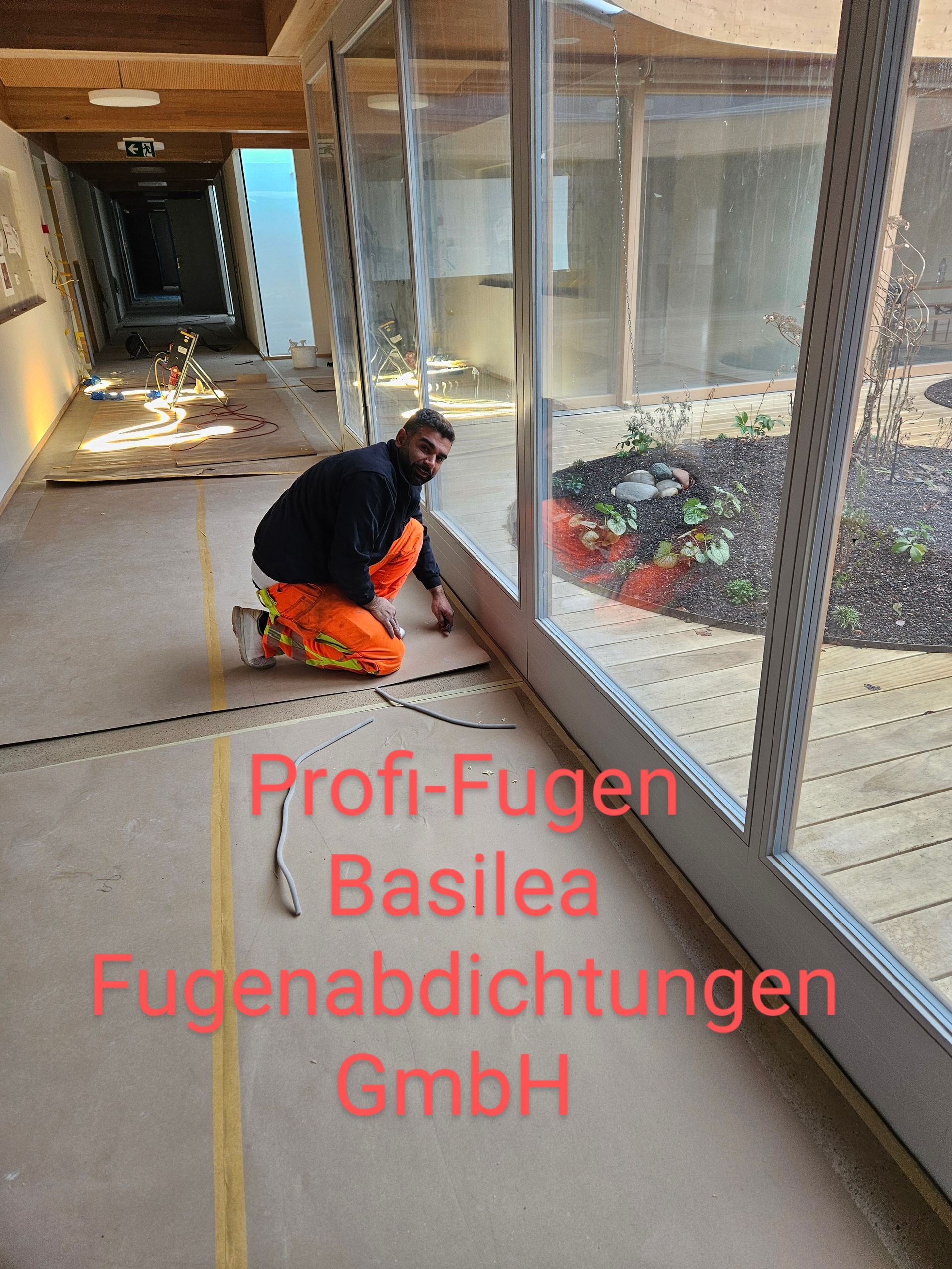 Ein Mann kniet vor einem großen Fenster auf dem Boden.