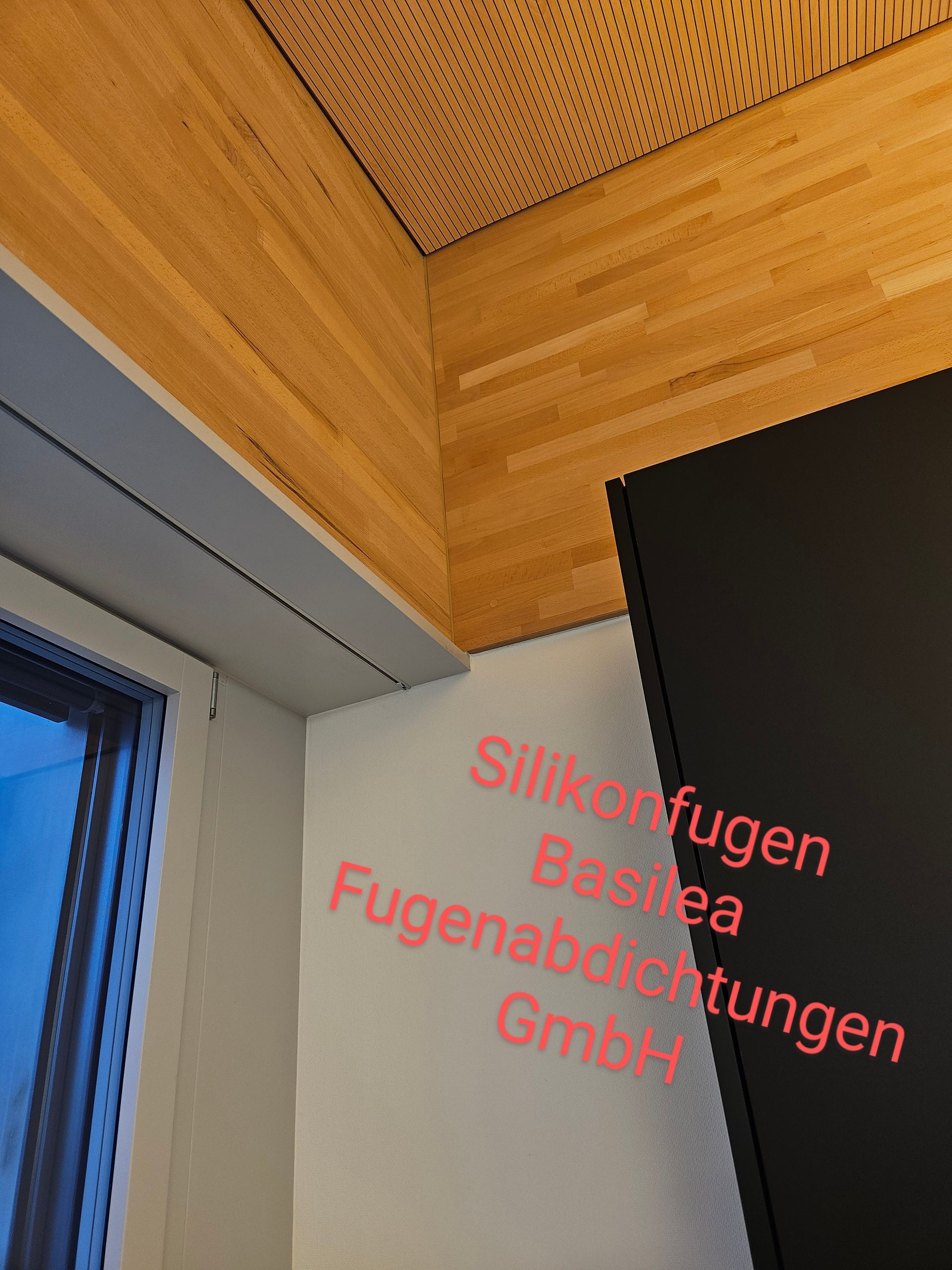 Eine Zimmerecke mit einem Schild mit der Aufschrift „Siliconfugen Basdea Fugenabdichtungen GmbH“