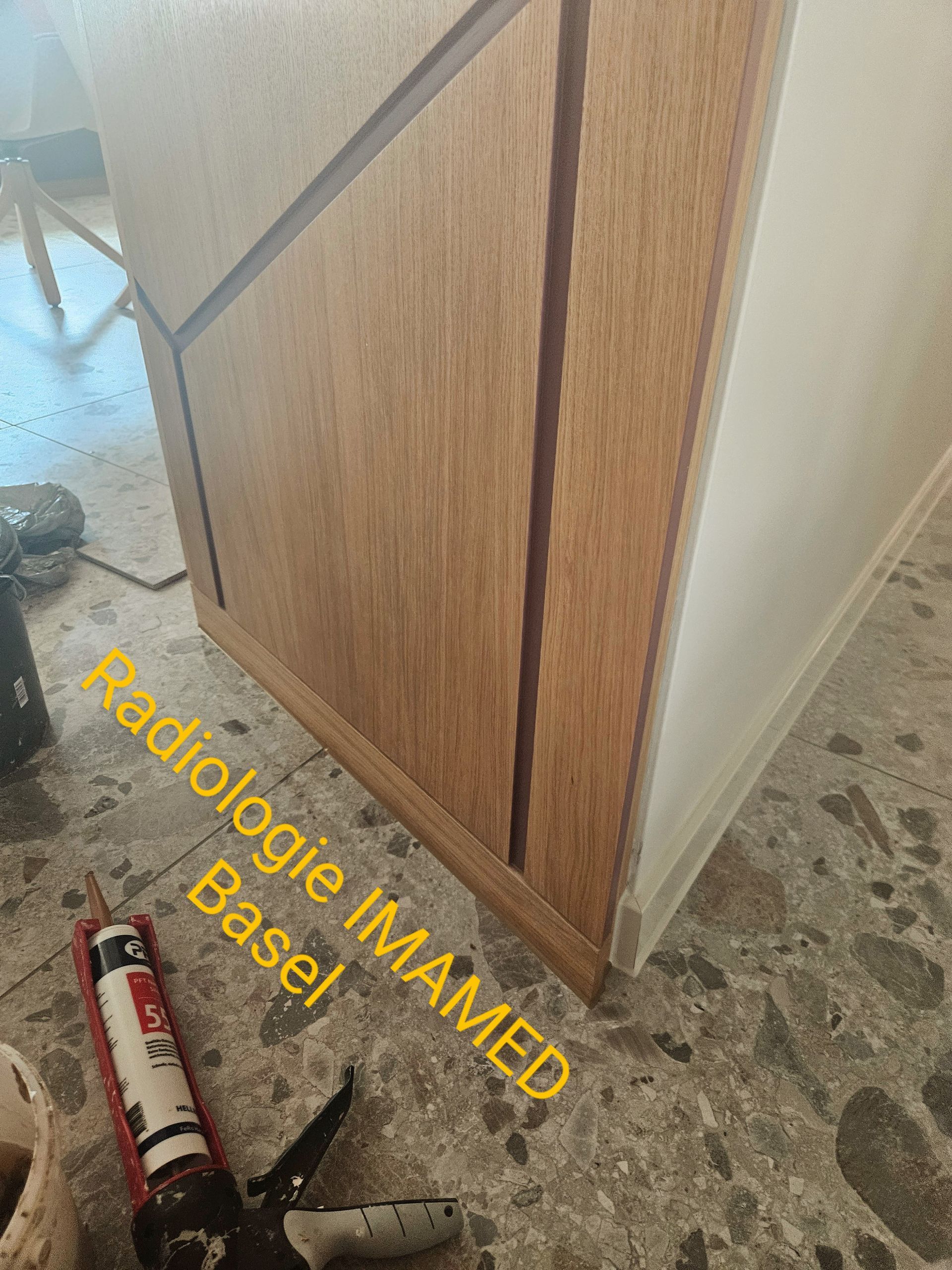 Eine Flasche Dichtungsmittel steht neben einem Holzschrank auf dem Boden.