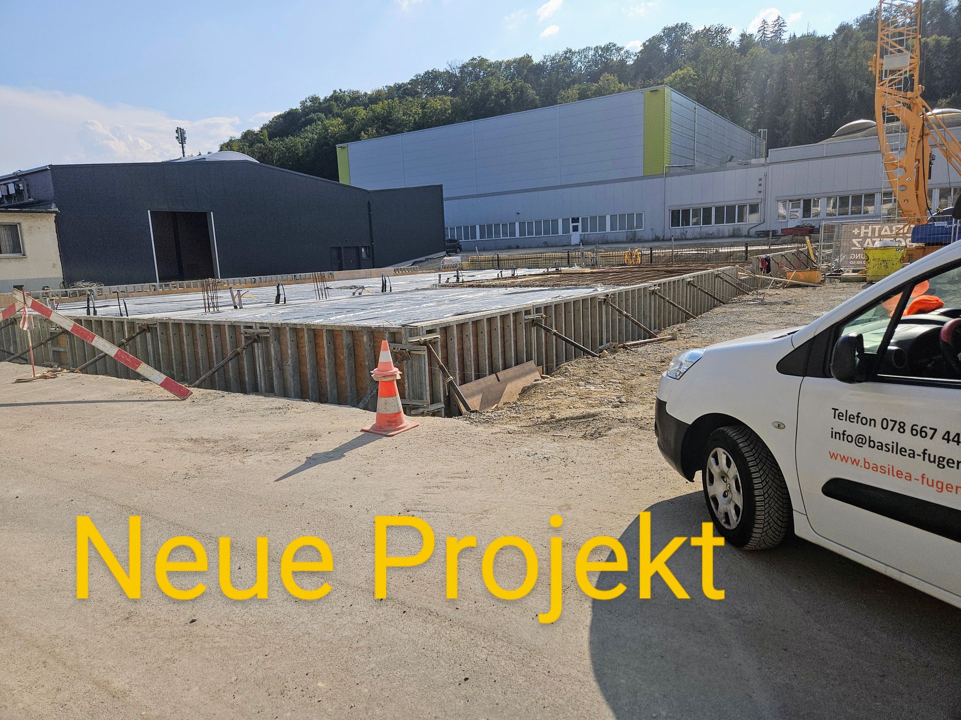 Ein weißes Auto steht vor einem Gebäude mit der Aufschrift „Neues Projekt“