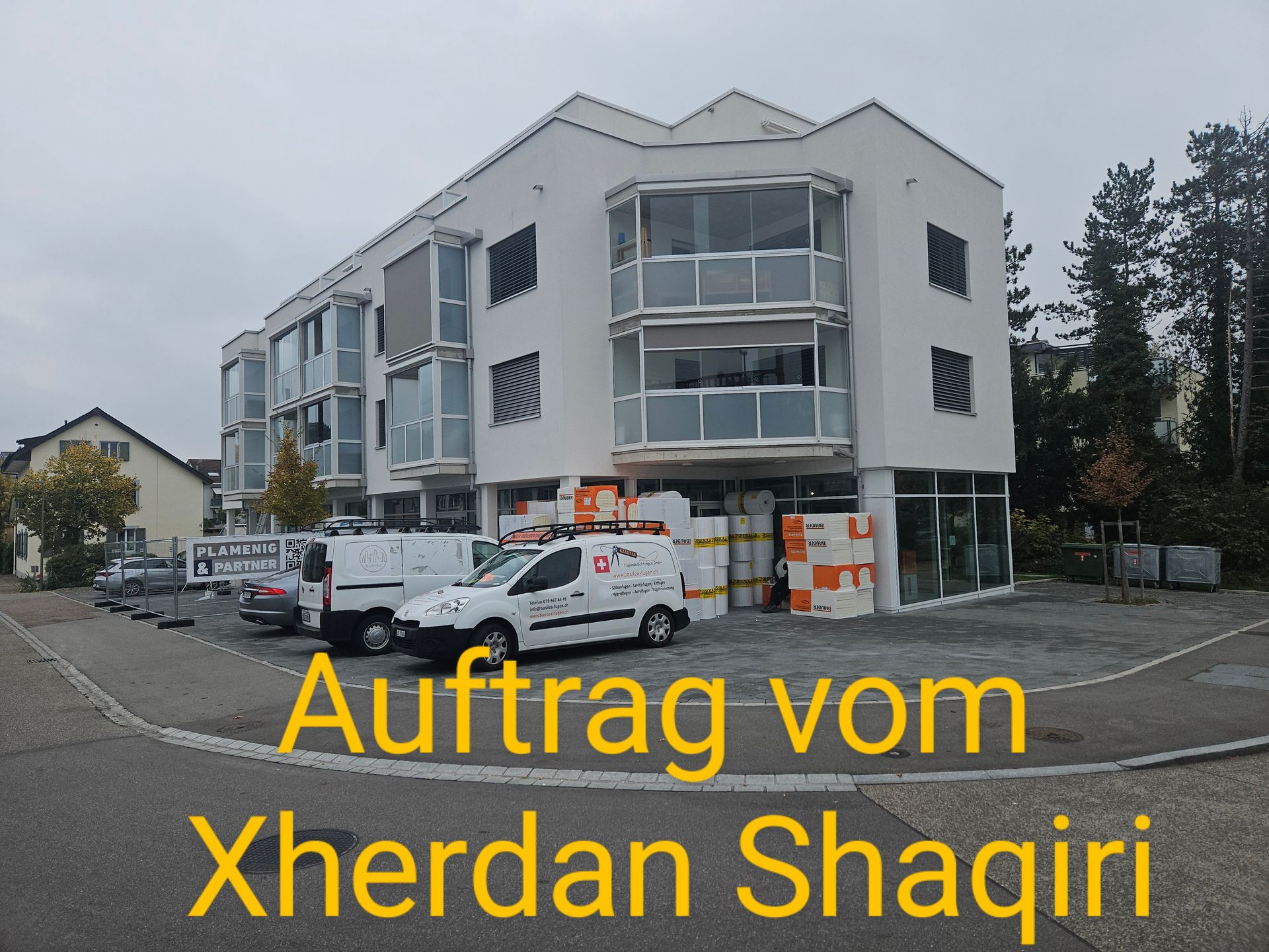 Vor einem Gebäude mit der Aufschrift „Auftrag von Xherdan Shaqiri“ steht ein weißer Lieferwagen.