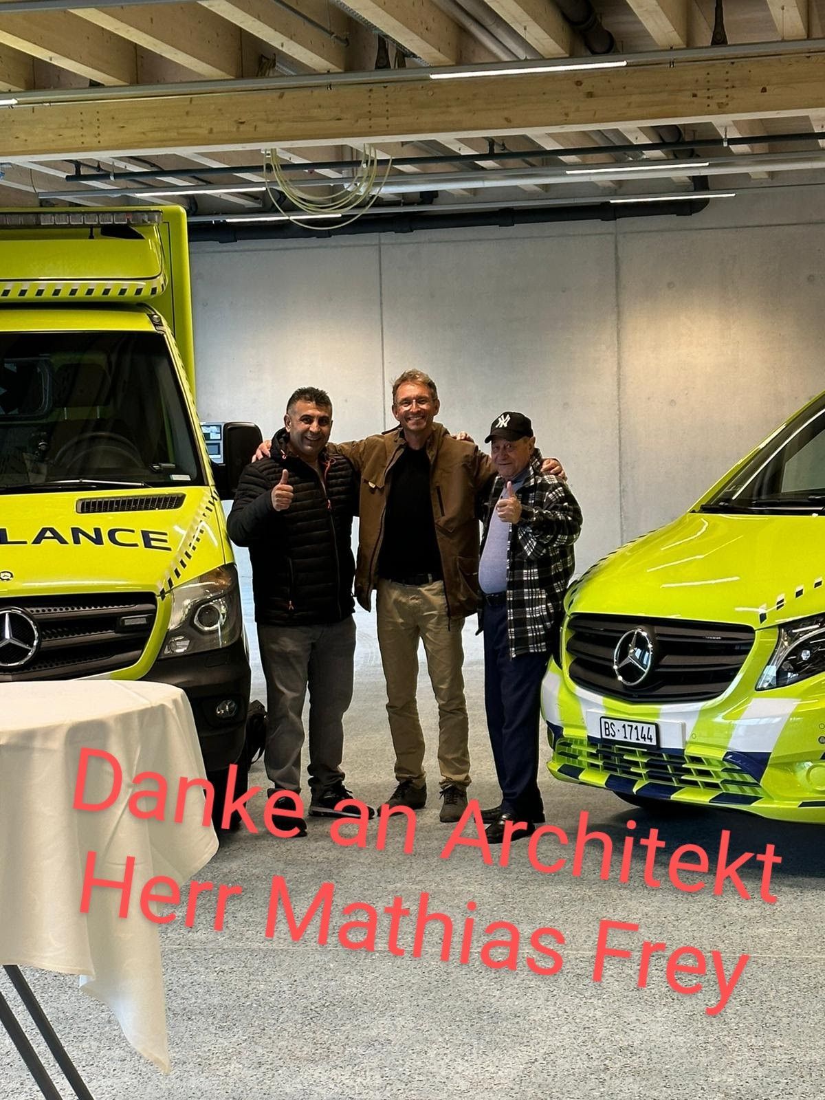 Drei Männer posieren vor einem Krankenwagen für ein Foto.
