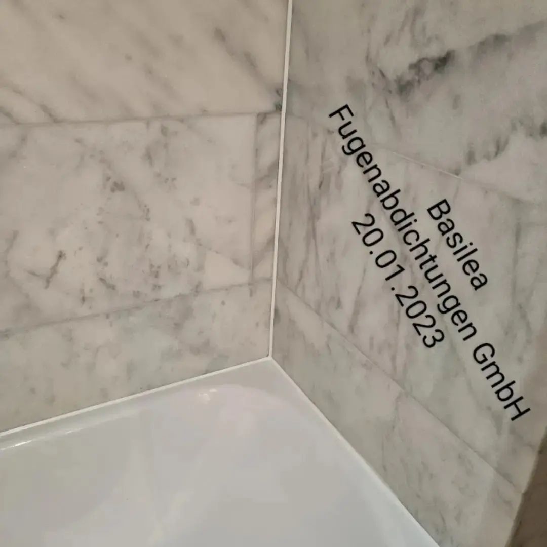 Eine Badezimmerecke mit Marmorwand und weißem Boden.