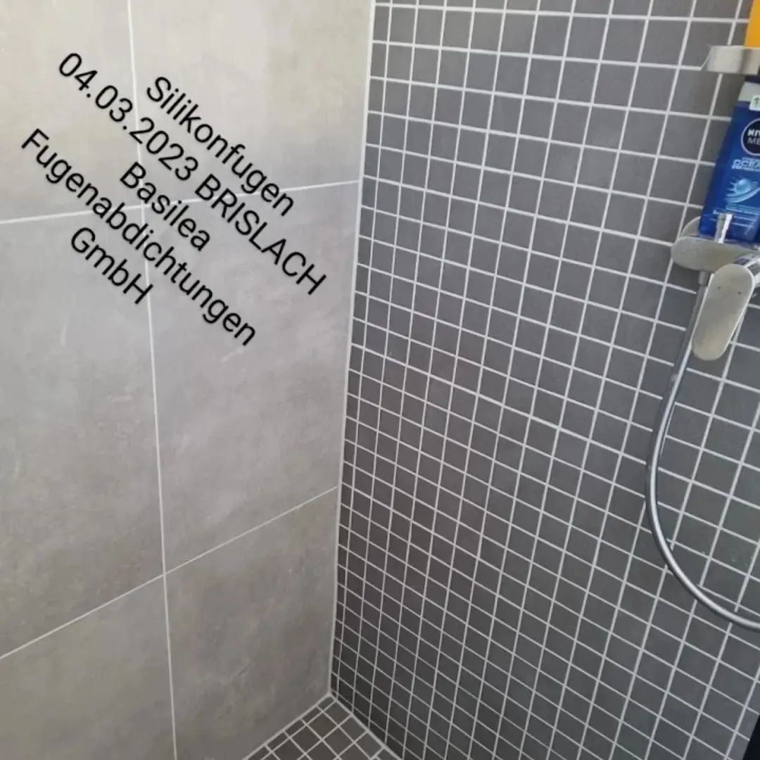Eine Dusche mit gefliester Wand und Duschkopf