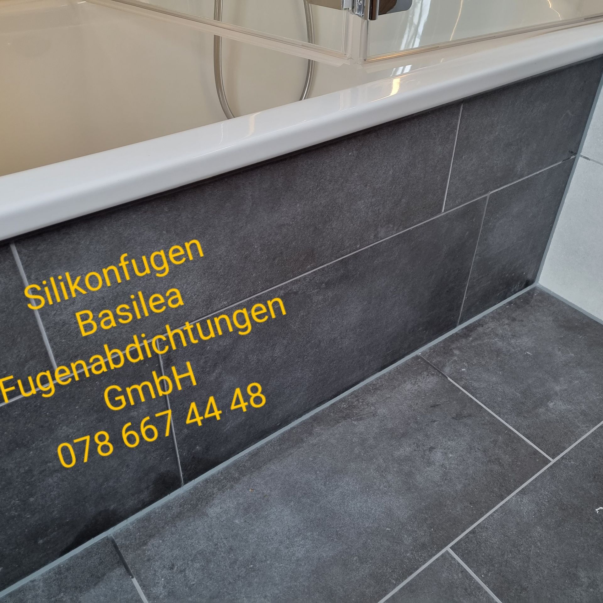 Ein Badezimmer mit Badewanne und einem Schild an der Wand mit der Aufschrift „Silikonfugen Basilea“