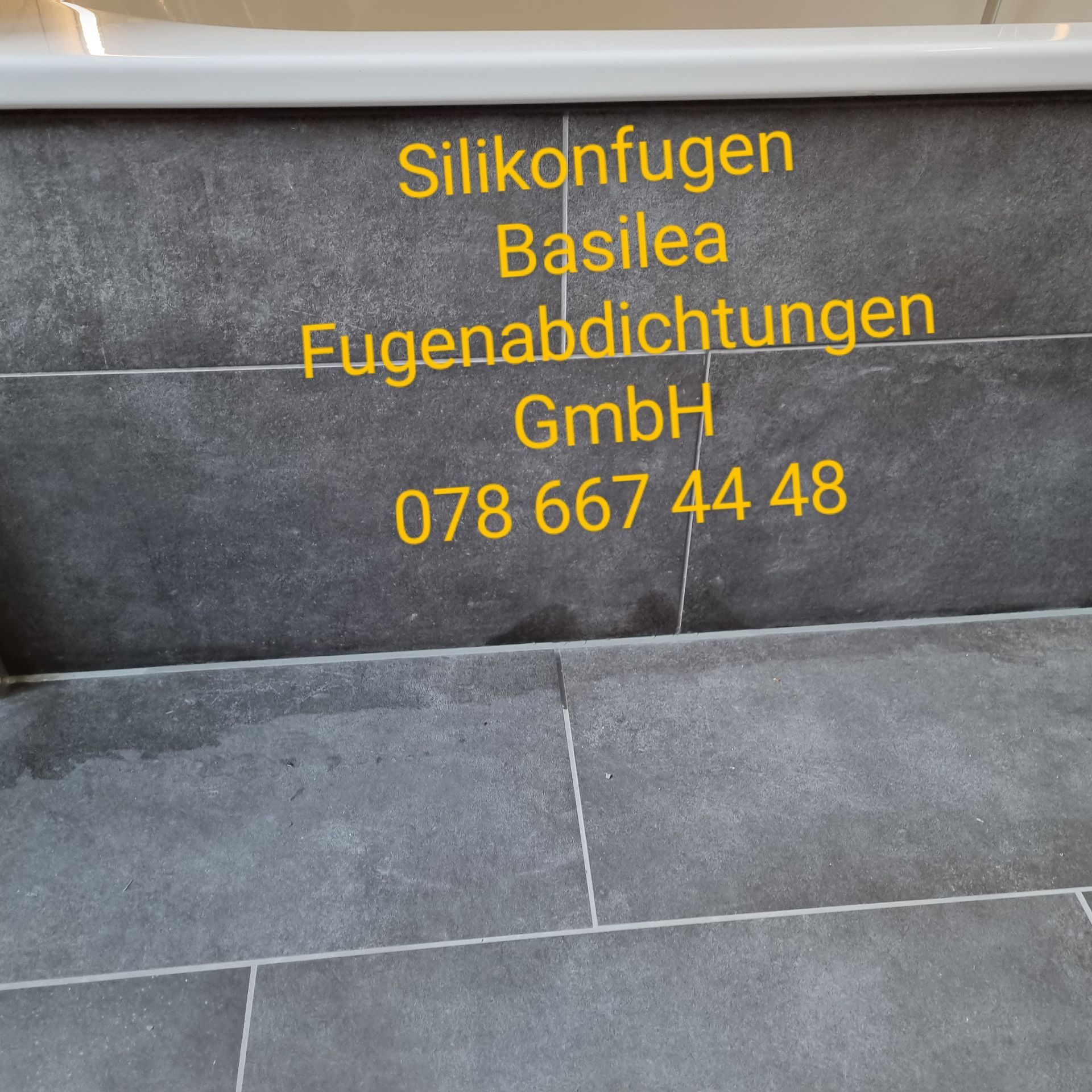 Ein Schild an einer Wand mit der Aufschrift „Silikonfugen Basilea“