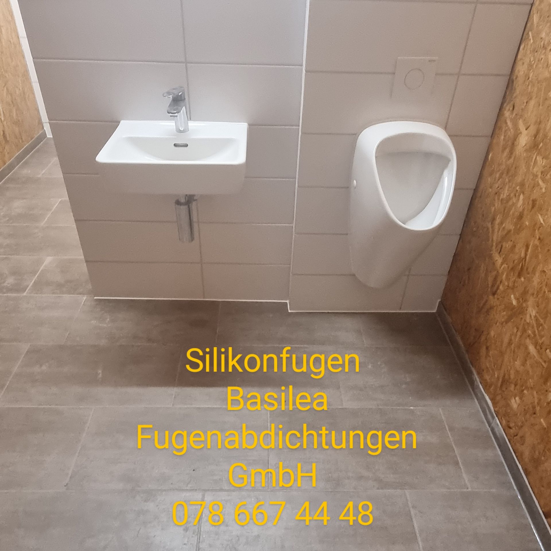 Ein Badezimmer mit Waschbecken und Urinal und einer Telefonnummer