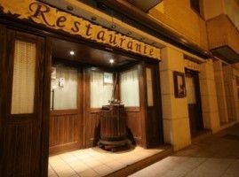 Entrada de restaurante con puerta de madera, cartel y decoración de barril.