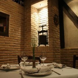 Interior de restaurante con paredes de ladrillo, una mesa puesta para cenar e iluminación decorativa.