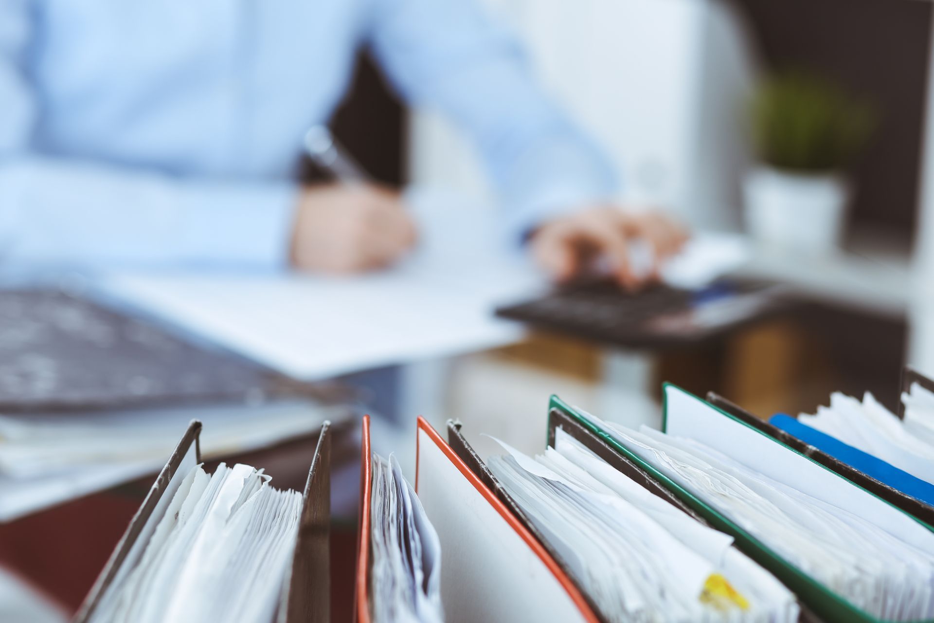 Personne travaillant à un bureau avec des classeurs au premier plan.