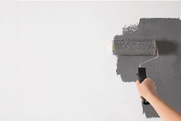 Farbrolle streicht eine Wand in Grau